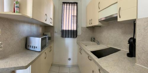 une cuisine avec des armoires blanches et un micro-ondes dans l'établissement Face mer, grand studio de 32m2, clim, wifi, parking, proche commerces, à Saint Cyprien Plage