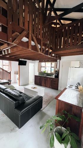 a living room with a black leather couch and wooden ceilings at Southside Getaway in Margaret River Town