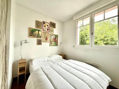 Un dormitorio con una gran cama blanca y una ventana. en Villa de charme à 2 pas de la plage, en La Teste-de-Buch
