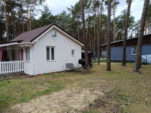 una casa bianca con una recinzione e alberi di Domek nad jeziorem Sławskim Radzyń k Sława 250m od jeziora a Radzyń