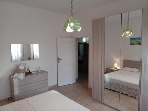 a white bedroom with a bed and a mirror at Semi-detached house, La Casa di Marinico in Alghero