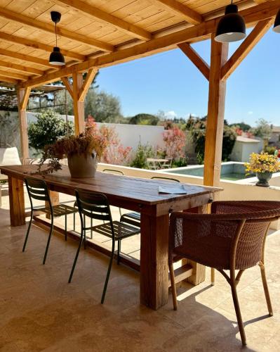 une table et des chaises en bois sur une terrasse dans l'établissement Les Cigales de Saint Quentin la Poterie, à Saint-Quentin-la-Poterie