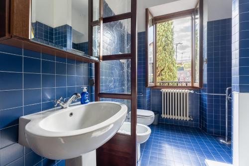 La salle de bains est pourvue de carrelage bleu, d'un lavabo et de toilettes. dans l'établissement Casa Preziosa - Salò, à Salò