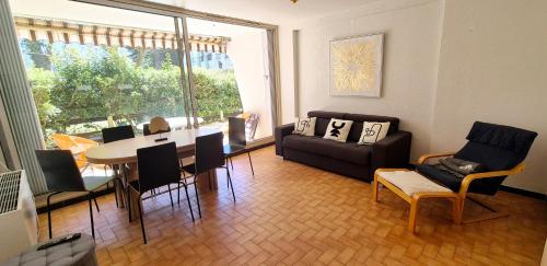 un salon avec un canapé, une table et des chaises dans l'établissement Appart 8 pers, 80M2, parking privée, Mer & lac à pied, Face parc aquatique, à La Grande Motte