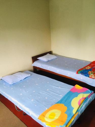2 Einzelbetten in einem Zimmer mit gedankenlosem, gedankenlosem, gedankenlosem, gedankenlosem in der Unterkunft Sams Cottage in Nuwara Eliya