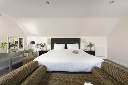 a bedroom with a large white bed with two chairs at Hustyns Hotel in Wadebridge