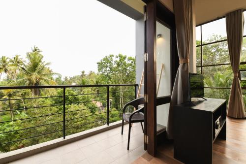 a room with a balcony with a view of trees at Hiriketiya Beach Resort in Hiriketiya