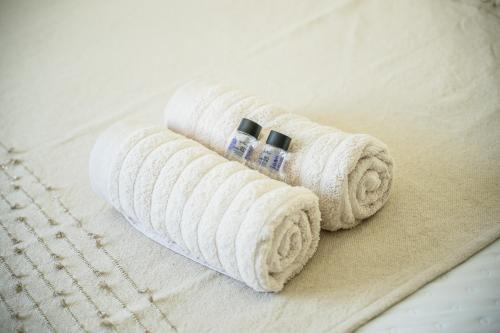 two rolls of white towels sitting on a bed at La Kaz Beaufond - T4 climatisée & familiale in Saint-Benoît