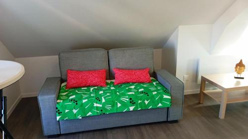 un canapé avec deux coussins rouges dans une pièce dans l'établissement Grand studio neuf au calme, à Reims