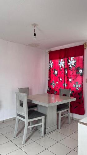 a dining room table with two chairs and a red curtain at Peace and quiet in Guadalupe