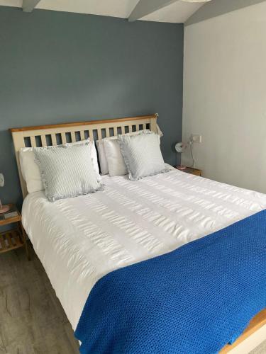 a bedroom with a large white bed with blue sheets at Pond Cottage in Coverack