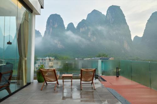 a balcony with chairs and a view of mountains at The One Hotel壹心生活美学酒店 in Yangshuo