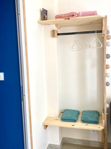 - un placard avec 2 serviettes vertes sur une étagère dans l'établissement La petite Escapade, à Calais