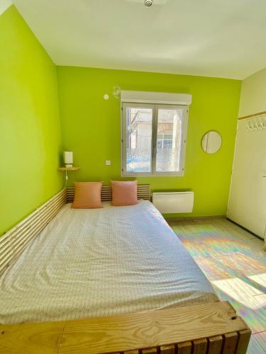 - une chambre avec un grand lit dans une pièce verte dans l'établissement La petite Escapade, à Calais