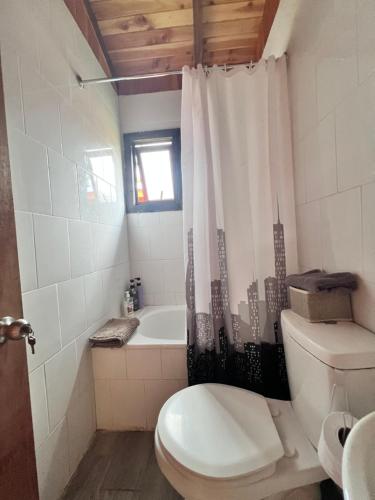 a bathroom with a toilet and a bath tub with a shower curtain at Cabañas NATURE in Gorbea