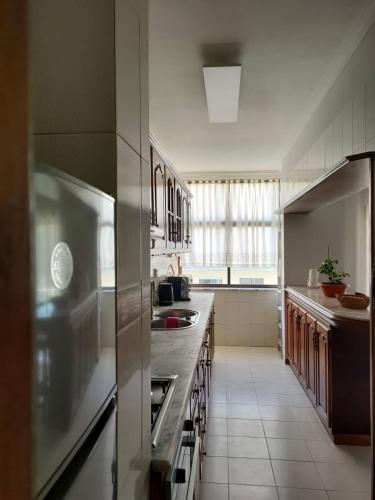 a kitchen with stainless steel appliances and a large window at Apartamento T2 Amorosa Beach in Viana do Castelo