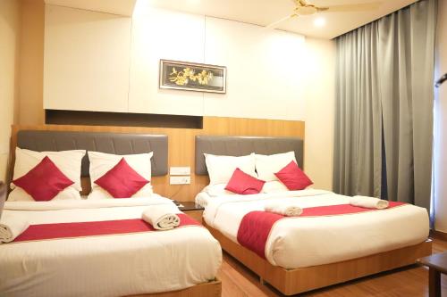 two beds in a hotel room with red pillows at KVP GOLDEN INN in Tirupati