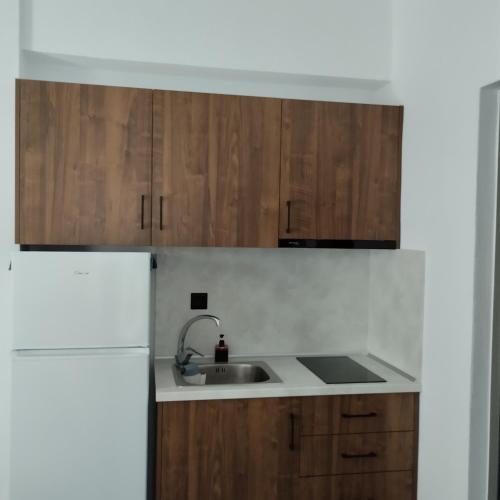 a kitchen with wooden cabinets and a sink at Thanos ,Rooms and Apartments in Ouranoupoli