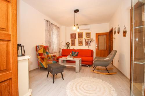 Una sala de estar con un sofá rojo y sillas. en Great location,2 bedroom apartment, en Cavtat