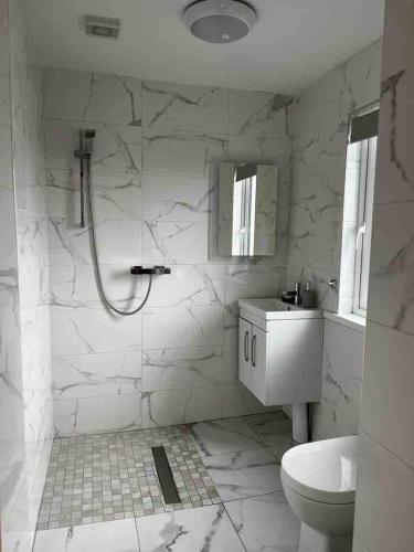 a white bathroom with a shower and a sink at River View - Modern 4 Bedroom Bungalow in Cabraghkeel