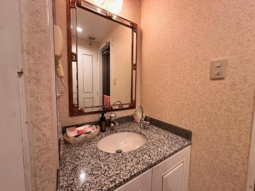 a bathroom with a sink and a mirror at ホテル ジョイ in Akashi