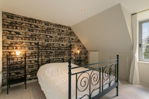 a bedroom with a brick wall next to a bed at La Délice in Érezée