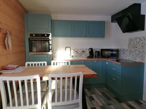 une cuisine avec des placards bleus et une table en bois dans l'établissement Les Marm'hôtes, à La Côte-dʼAime