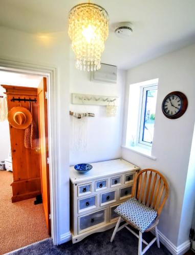 a room with a dresser and a clock and a chair at Cozy Cotswold getaway near Burford in Shilton