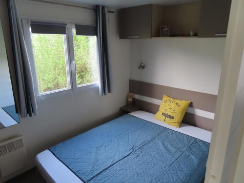 une petite chambre avec un lit et deux fenêtres dans l'établissement Mobile home dans un camping à saint Arnoult, à Saint-Arnoult