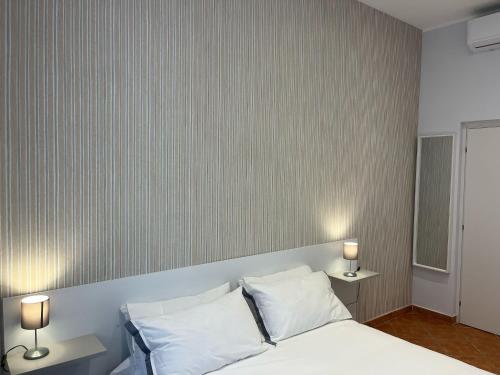 a bedroom with a white bed with two lamps at L'Aurora Casa Vacanze in Anzio