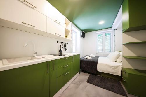 Una cocina verde y blanca con una cama y un fregadero. en Old City Micro-apartments, en Zadar