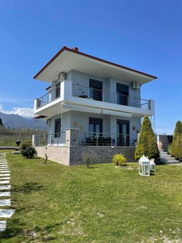 a large white house on top of a grass field at Plaka Luxury Villa in Litochoro