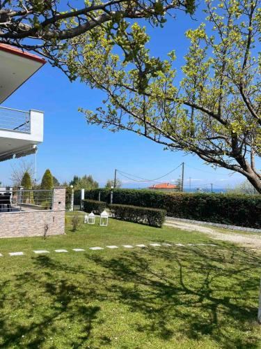 a park with two white chairs in the grass at Plaka Luxury Villa in Litochoro