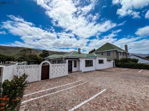 a house with a white fence and a driveway at Hermanus Backpackers & Budget Accommodation in Hermanus