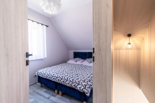 a bedroom with a bed with a blue and white comforter at Top Alex domki Międzyzdroje Lubin in Międzyzdroje