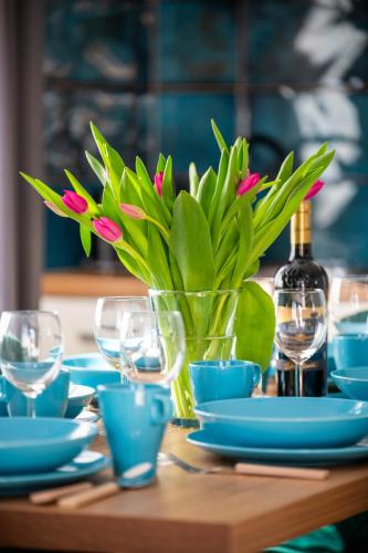 a table with blue plates and a vase with pink flowers at Top Alex domki Międzyzdroje Lubin in Międzyzdroje