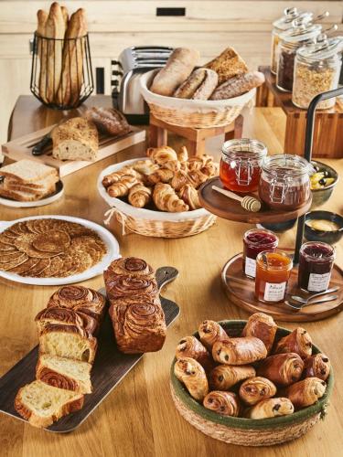a table with many different types of bread and pastries at Campanile Strasbourg - Illkirch Geispolsheim in Geispolsheim