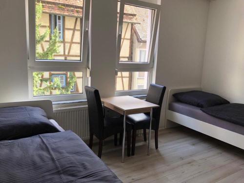 a bedroom with a table and chairs and two windows at Neu saniert, 7 Personen, direkt an der Autobahn und Mercedes Werk in Sindelfingen