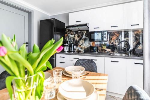 a kitchen with white cabinets and a wooden table at Top Alex domki Międzyzdroje Lubin in Międzyzdroje