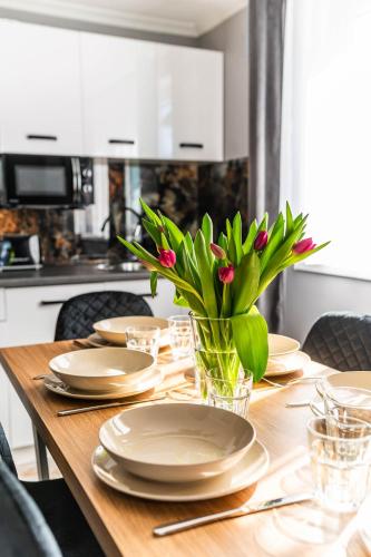 a wooden table with plates and a vase with flowers at Top Alex domki Międzyzdroje Lubin in Międzyzdroje