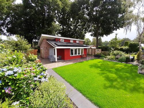 a small red house in a garden with a lawn at Vakantievilla-Ermelo in Ermelo