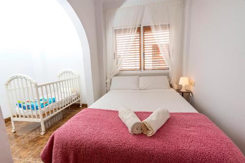 a bedroom with a bed with a red blanket and a crib at Lo Jardí de Benifallet in Benifallet