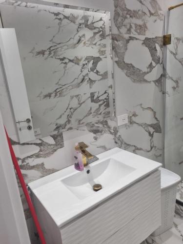 a bathroom with a white sink and a marble wall at Kodra e diellit residence 2 in Selitë e Vogël