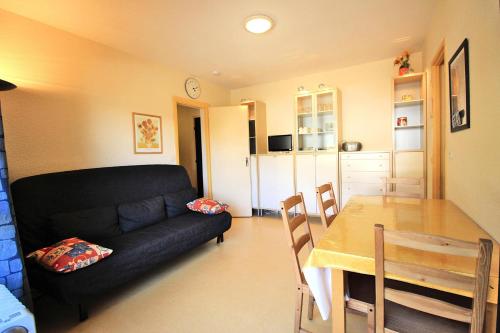un salon avec un canapé noir et une table dans l'établissement Résidence Les Campanules - LES CAMPANULES - CA52FC MAE-3107, à Villarodin-Bourget
