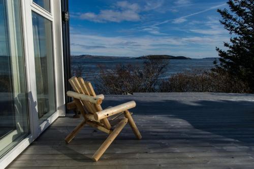 a wooden chair sitting on a porch looking out at the water at Thingvellir Chateau in Selfoss