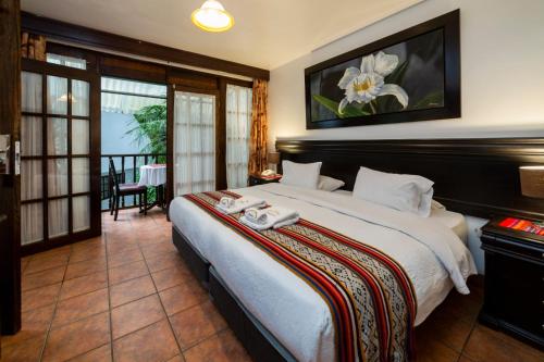 a bedroom with a large bed and a balcony at Gringo Bill's Boutique Hotel in Machu Picchu
