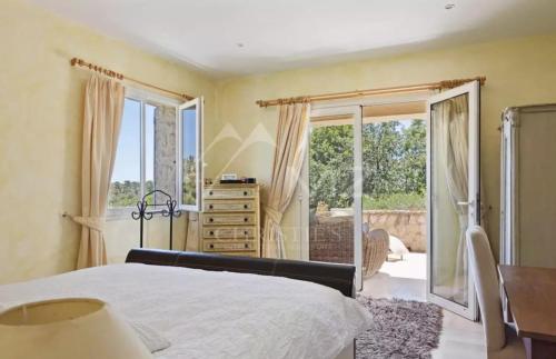 une chambre avec un lit, un bureau et des fenêtres dans l'établissement Mas Provencal d'exception Le lezard Bleu vence, à Vence
