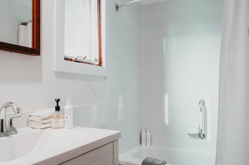 a white bathroom with a sink and a shower at The Kent Motel in Niagara on the Lake