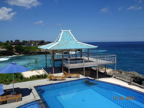 a swimming pool with a gazebo next to the ocean at Cliff Park Lembongan in Nusa Lembongan