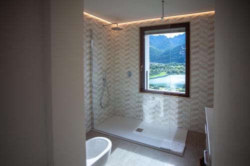 Le Cornici Home Suites - Apartments - Lake Idro في Ponte Caffaro: حمام مع دش ومرحاض ونافذة